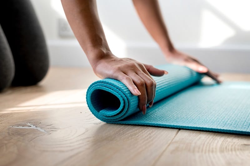 person rolling out blue non slip yoga mat