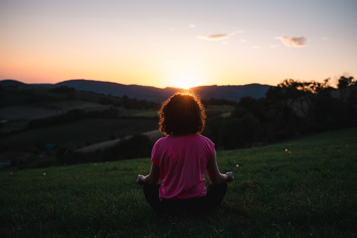 woman meditating at sunset