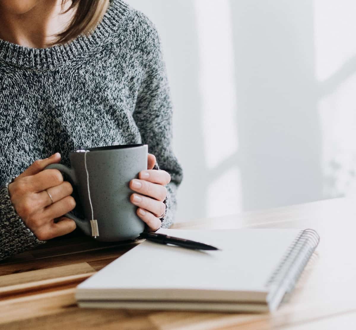 woman sat with journal and cup of hot tea