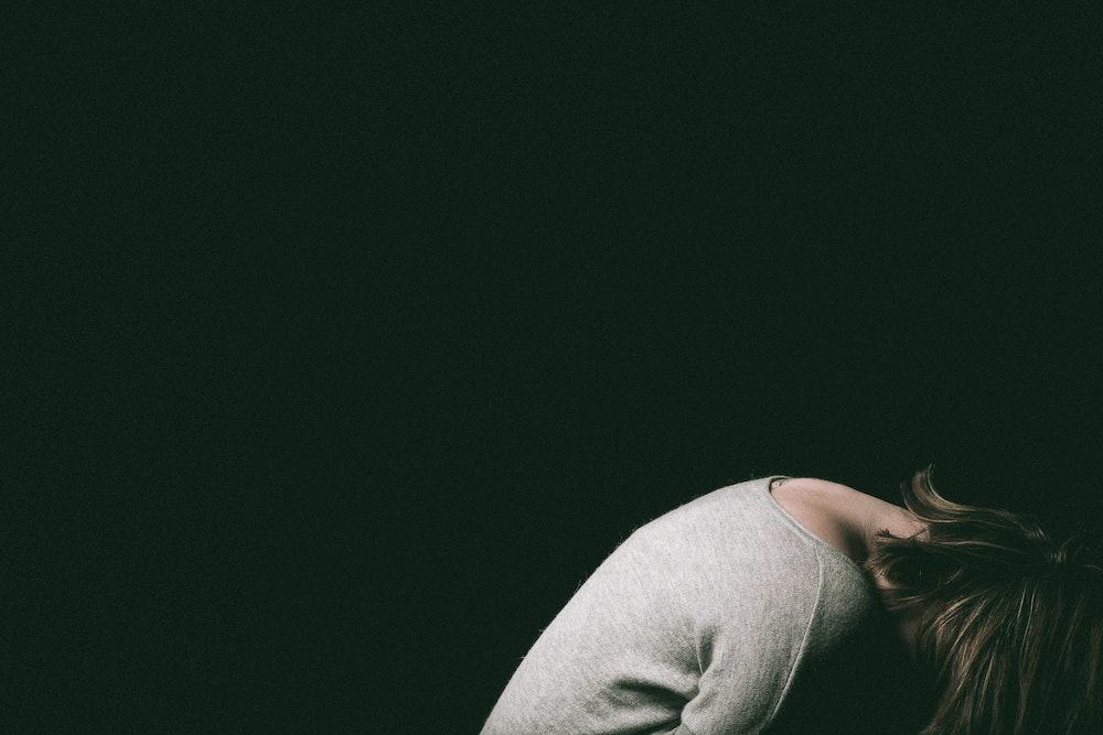 woman with head down looking sad
