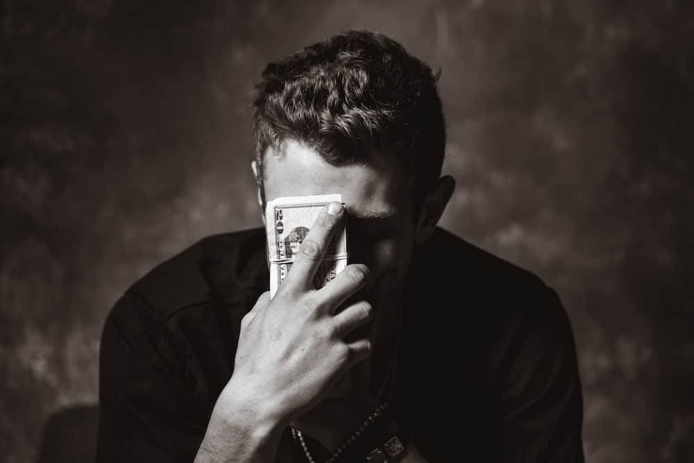 person holding head in hands with money