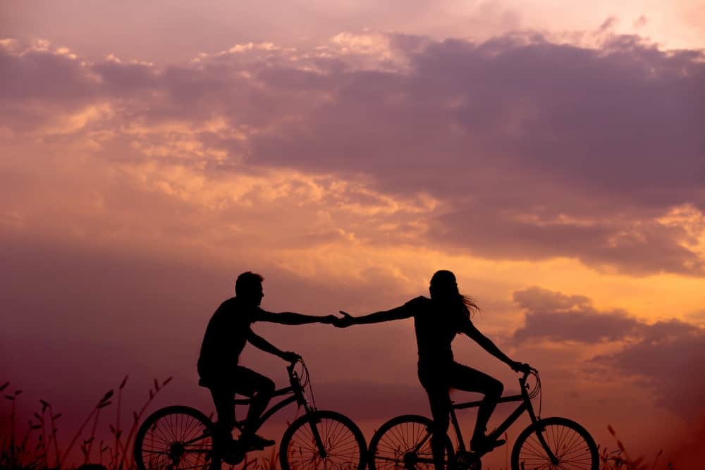 steps to manifesting a specific person couple holding hands on bikes at sunset