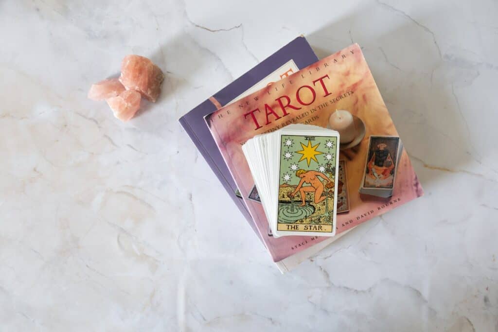The 21 Best Tarot Gifts for Birthdays and the Holidays in 2024 31 tarot deck pictured on top of tarot book stack alongside rose quartz crystals on a white marble background