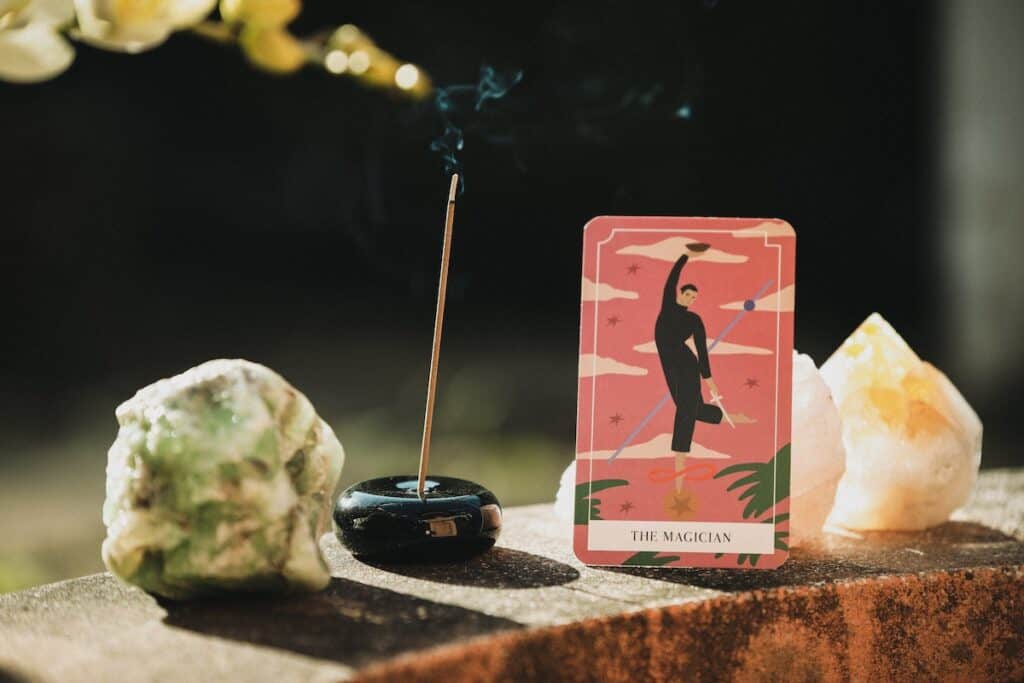 the magician tarot card placed upright next to incense stick and three crystals