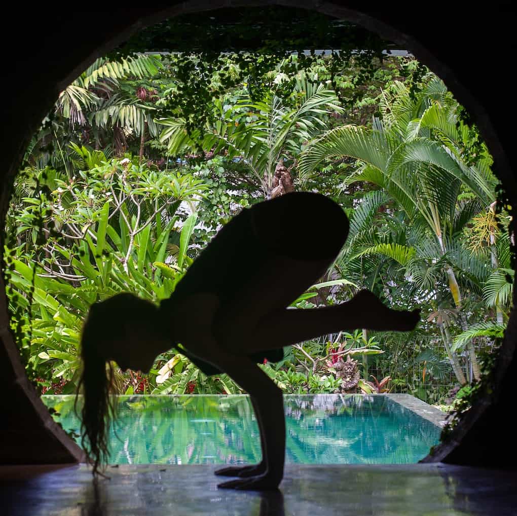 12 Spiritual Self Care Ideas for a Healthy Soul 5 girl practicing crow yoga pose in front of pool and jungle background in Bali