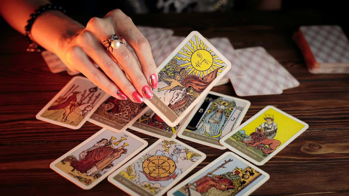 woman completing a tarot spread holding the sun tarot card