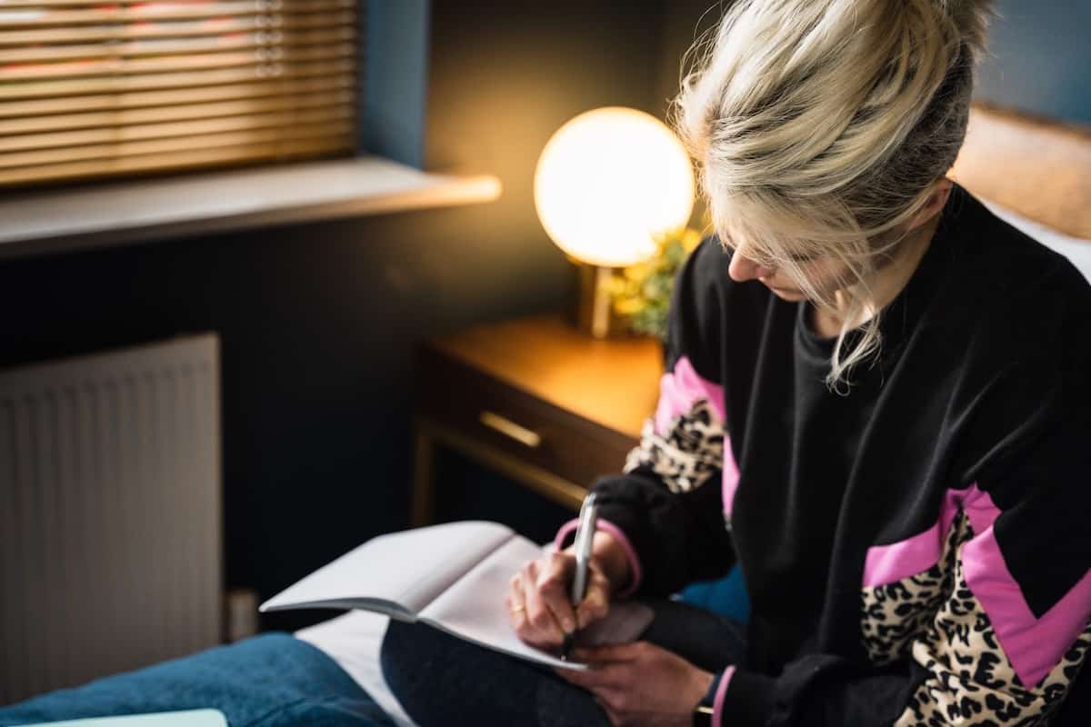 woman with head down writing in journal