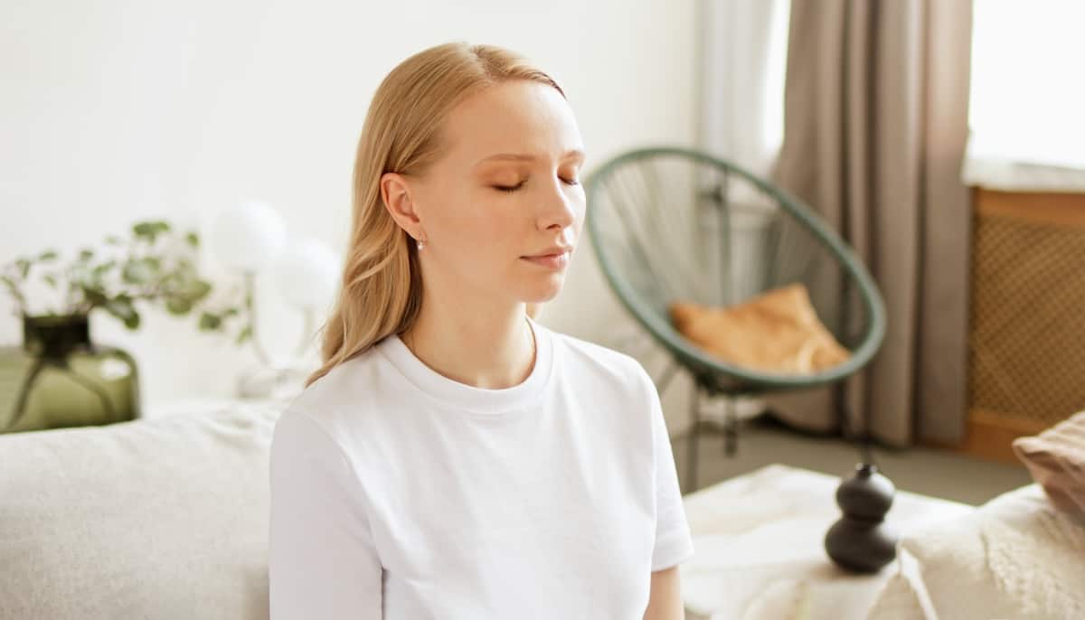 22 Simple Ways to Practice Emotional Self Care 10 Woman with closed eyes doing breathing meditating practices at home. Making deep breath-exhalation pranayama exercises.