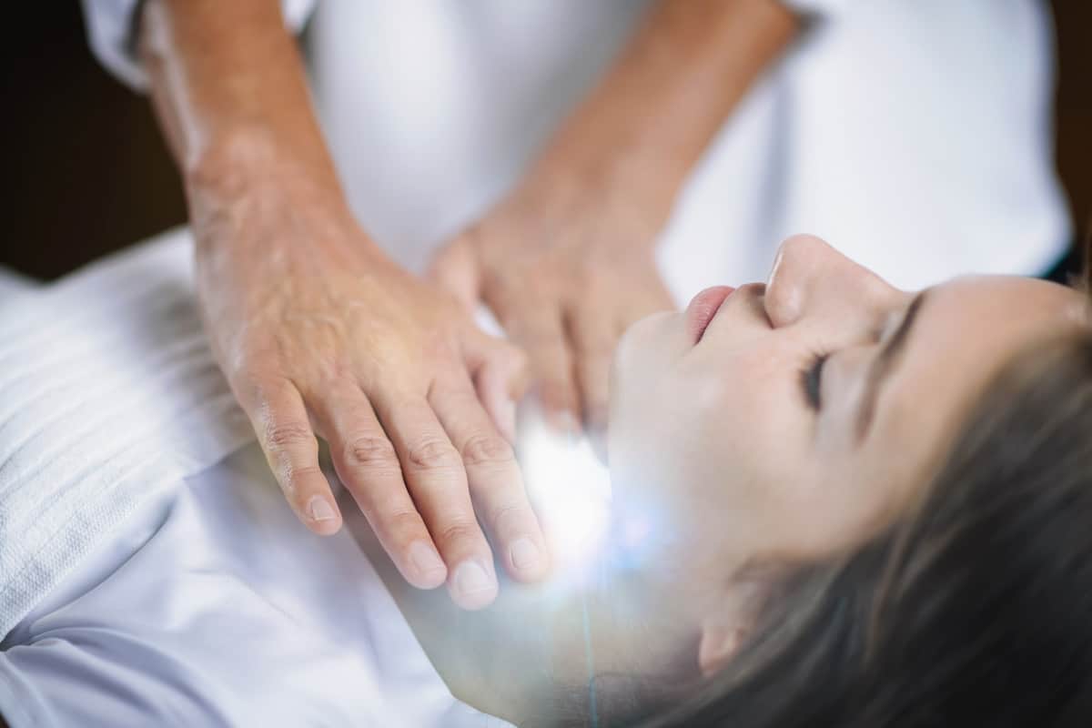 woman receiving energy work - white light radiating from her throat chakra