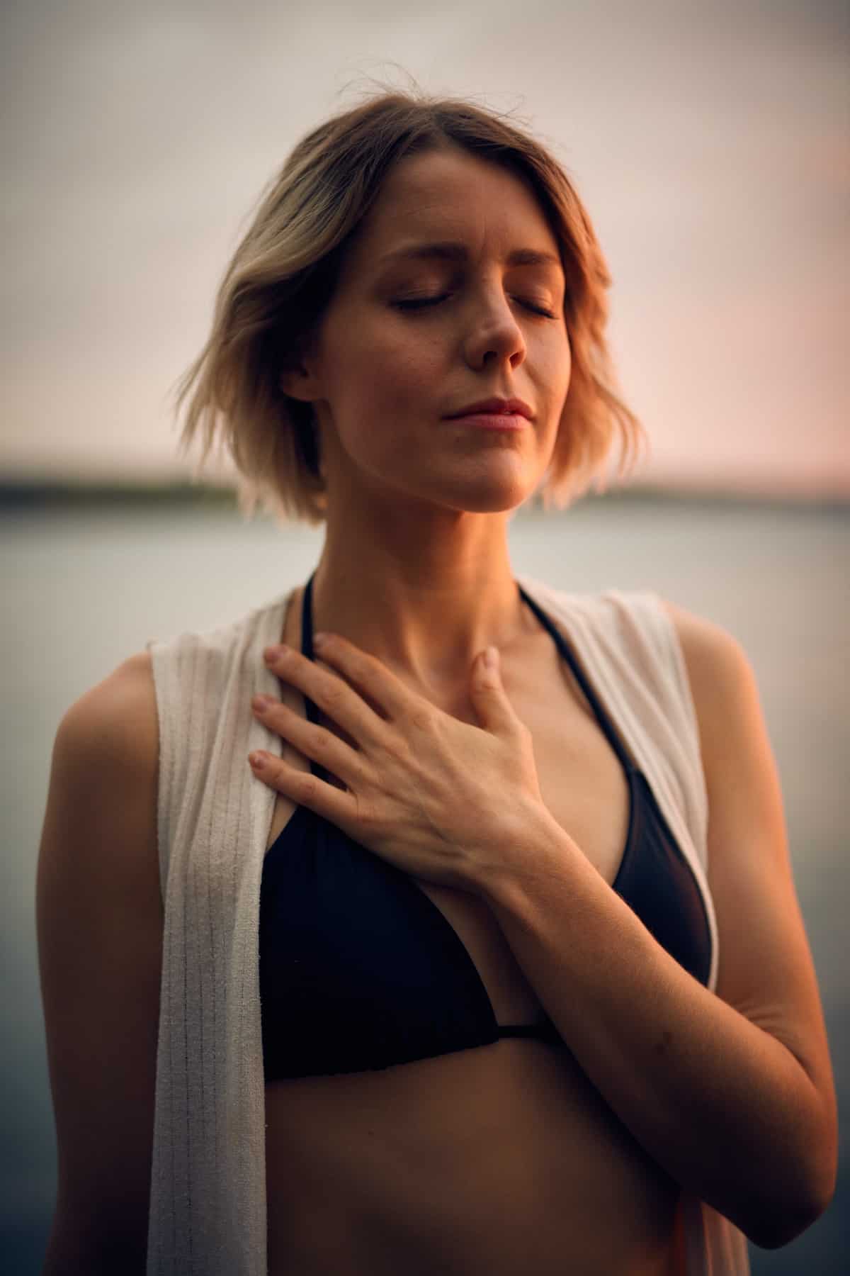 woman with eyes closed placing hand over heart space