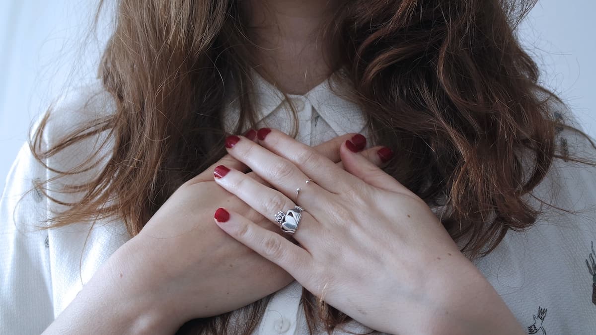 woman placing hands over heart chakra area