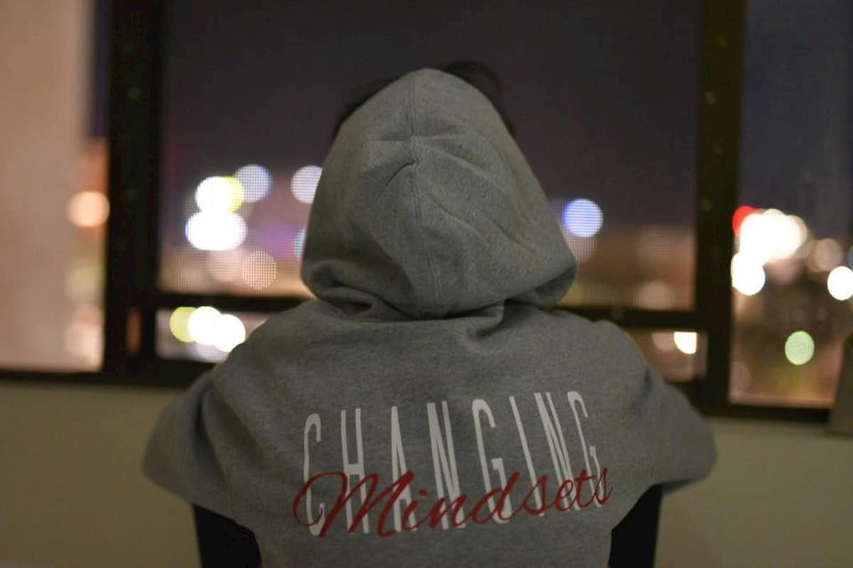 back of person wearing hoodie with slogan saying "changing mindsets"