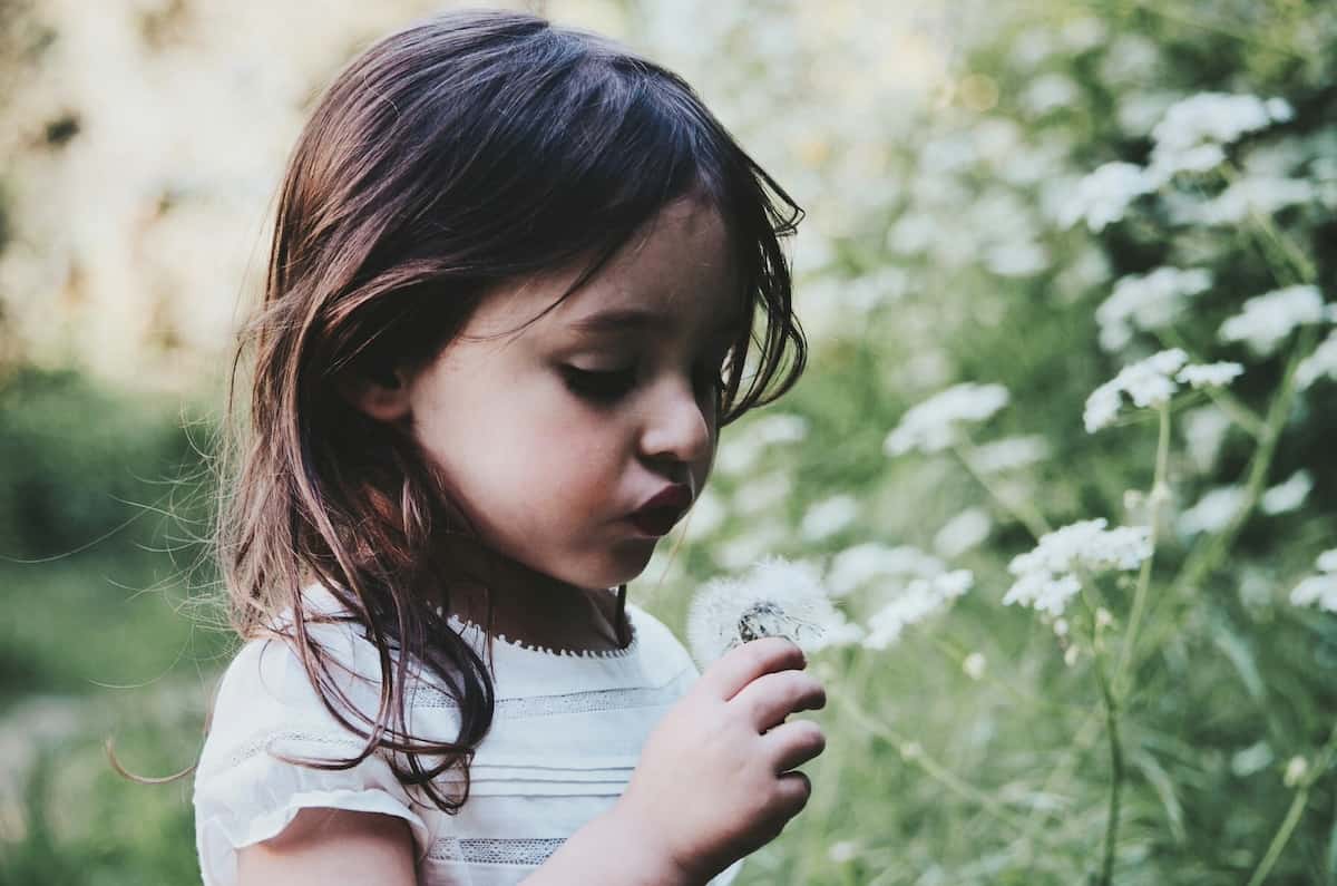 young girl blowing dandelion