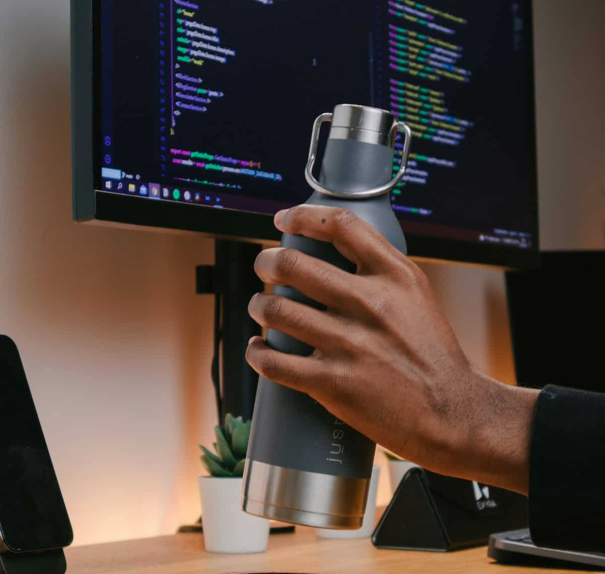 person working from home at computer staying hydrated with water bottle