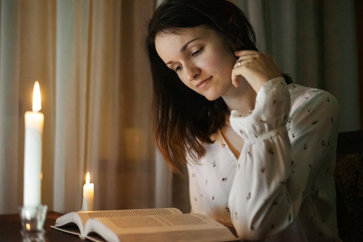woman reading by candlelight at night